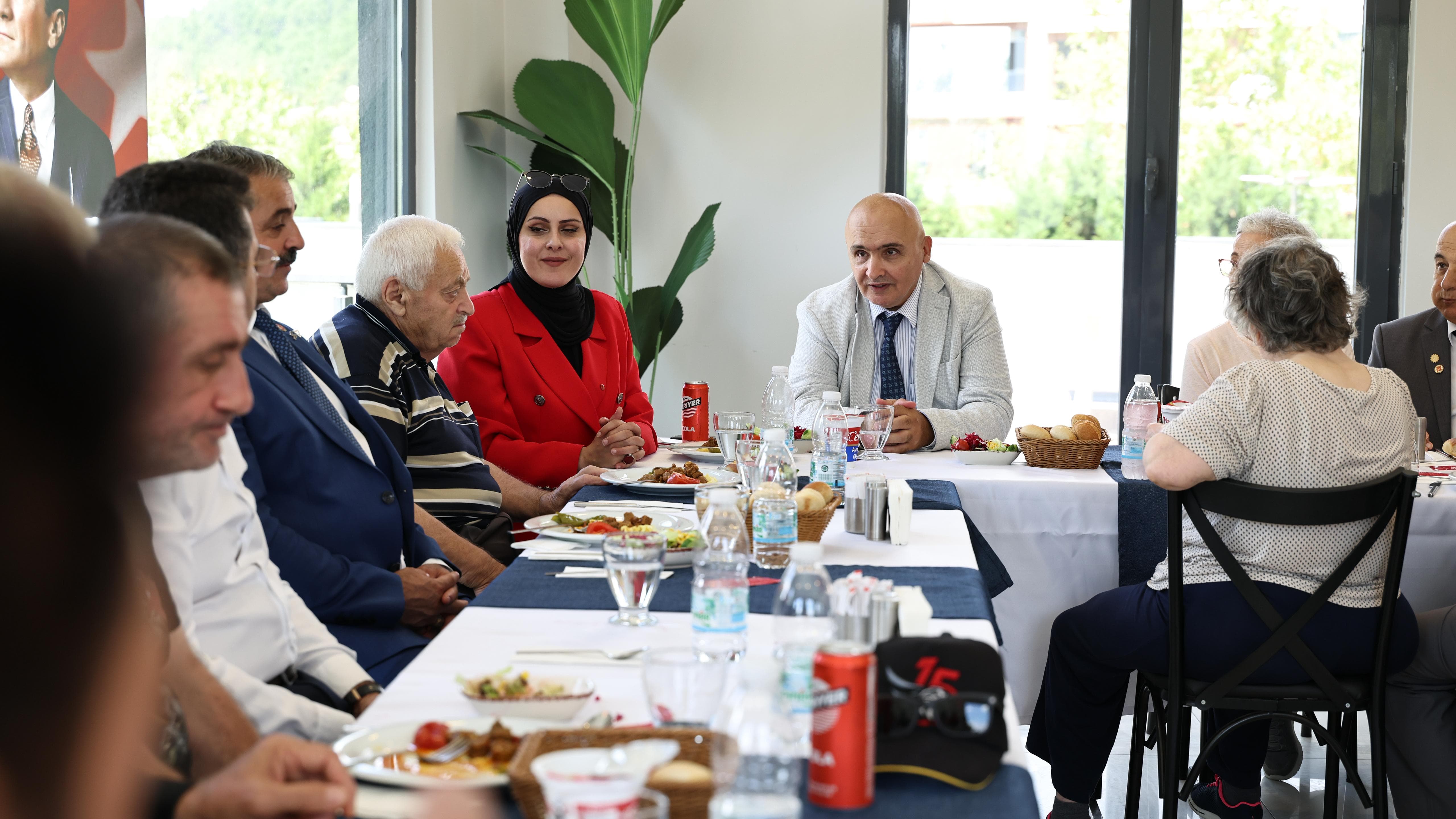 Dernek üyeleri ve misafirlerin birlikte oturduğu yemek masası